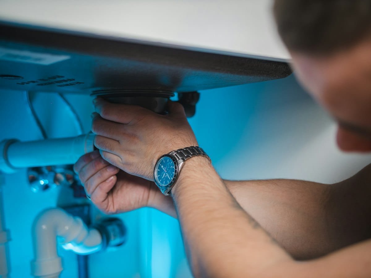 Technician repairing plumbing under a sink